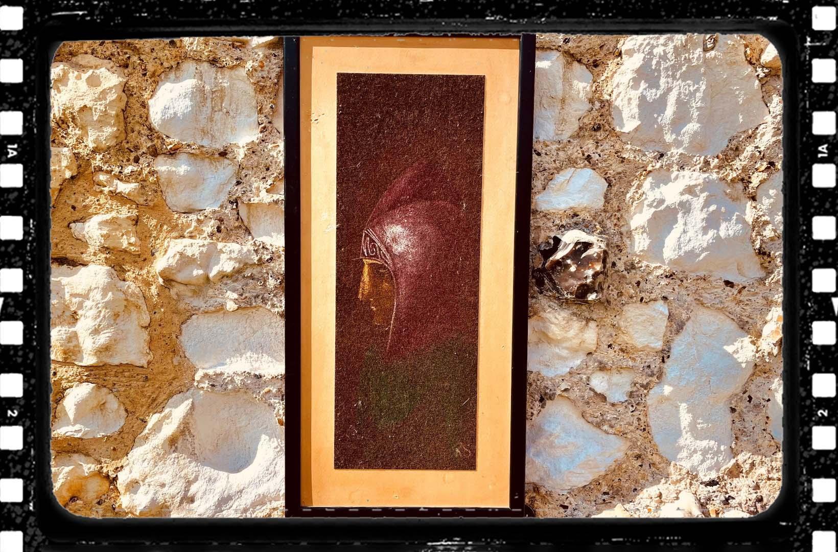 Photo of a framed portrait of a monk on a sandy coloured stone wall. A celluloid film frame is overlaid onto the image to make it look cinematic.