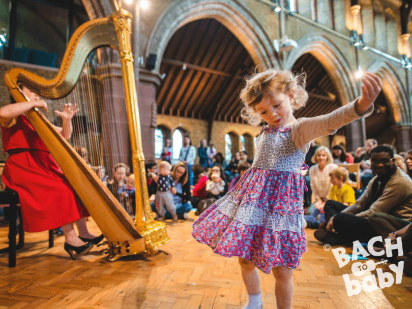 child dancing to harpist at bach to baby concert 