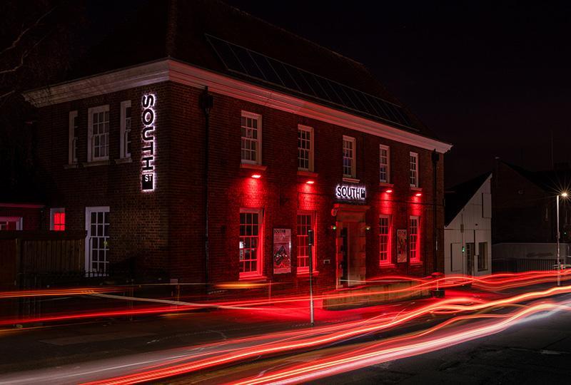 Timelapse photo of the South Street building at night, bathed in red light from its external lighting.