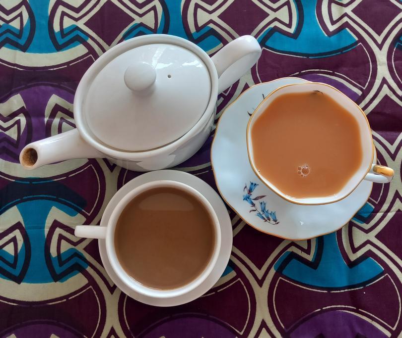 An Image of a coffee cup and teapot on a brightly coloured, African inspired tablecloth