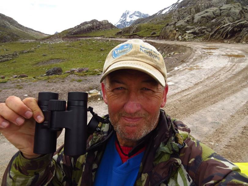 Photo of Gary Prescott in a baseball cap, holding up his binoculars