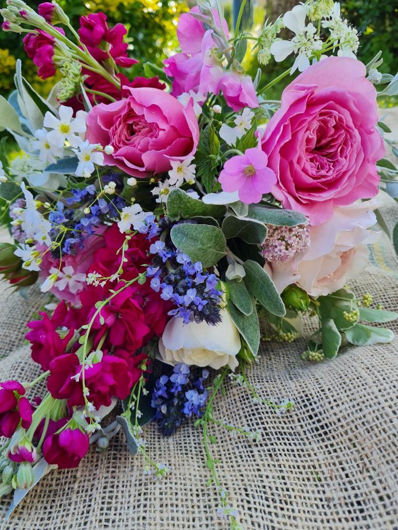 Bouquet of pink, lilac, white and maroon flowers lying flat on a hessian sack