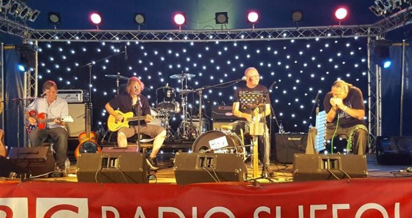 four men on stools on stage