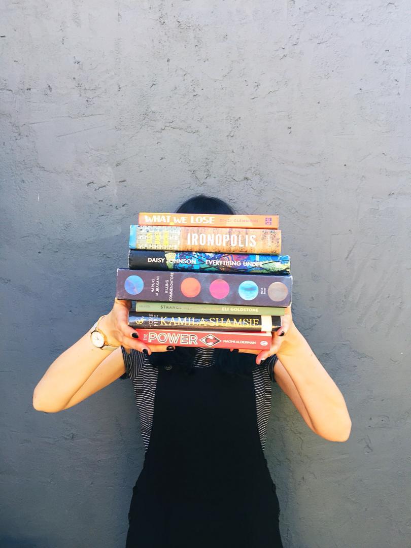woman holding a pile of files in front of her face