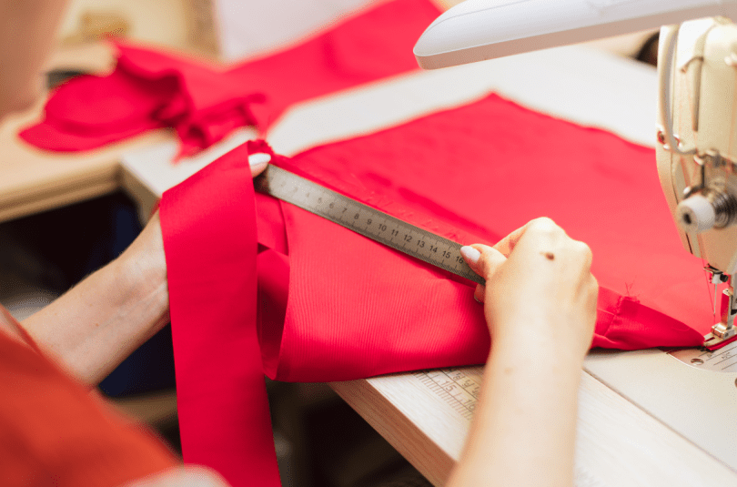 Hands measuring red fabric