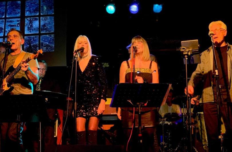 band performing on stage - two female vocalists and two male guitarists