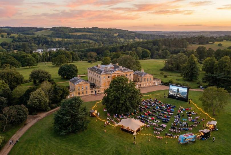 An aerial shot of Basildon Park incorporating the mansion house and parkland with the Outdoor cinema experienced visualised on the front lawn