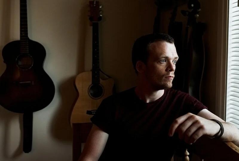 Chris Fox sitting in front of his guitars