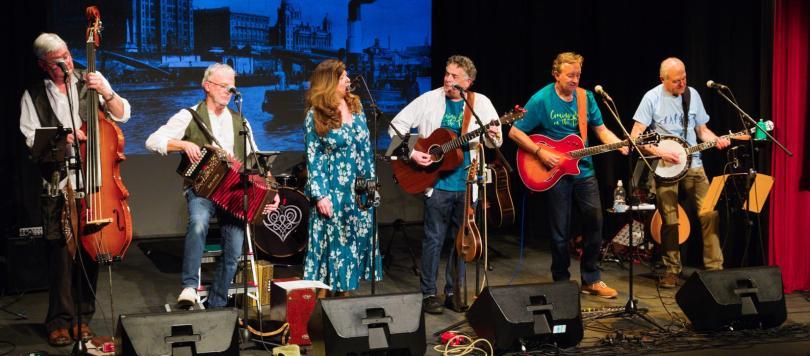 Photo of a band on stage with melodeon, guitars, banjo and double bass