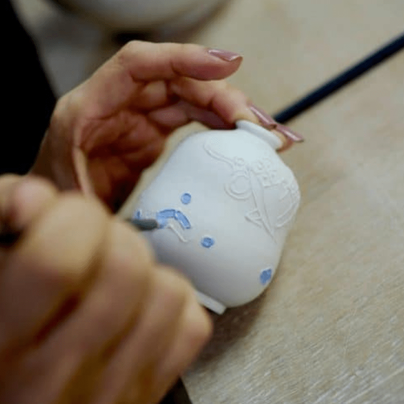 Hand colouring a ceramic pot