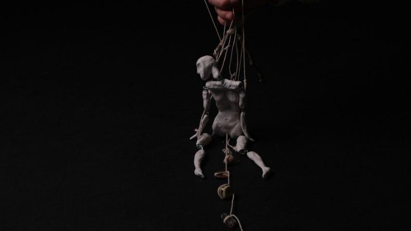a puppet hanging on a black background