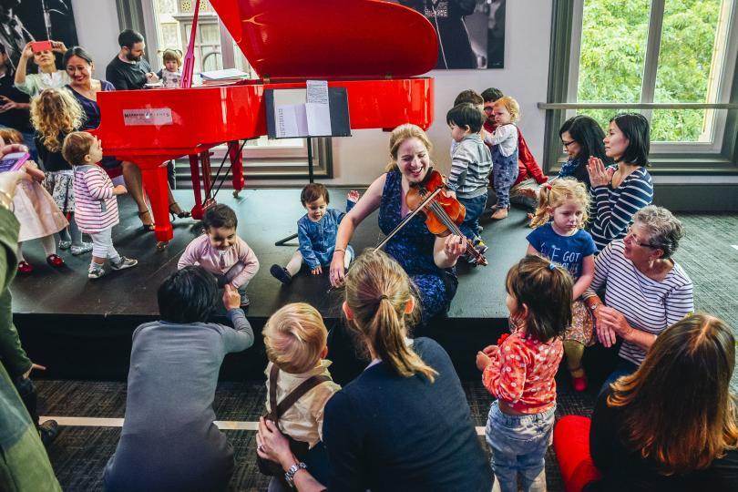 Violinist surrounded by children at a concert