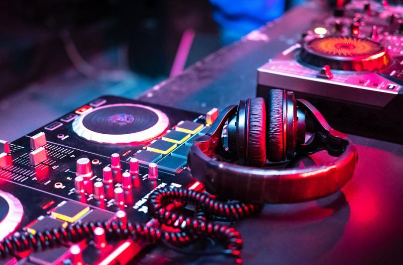 Stock image of DJ decks and headset bathed in pink and blue light