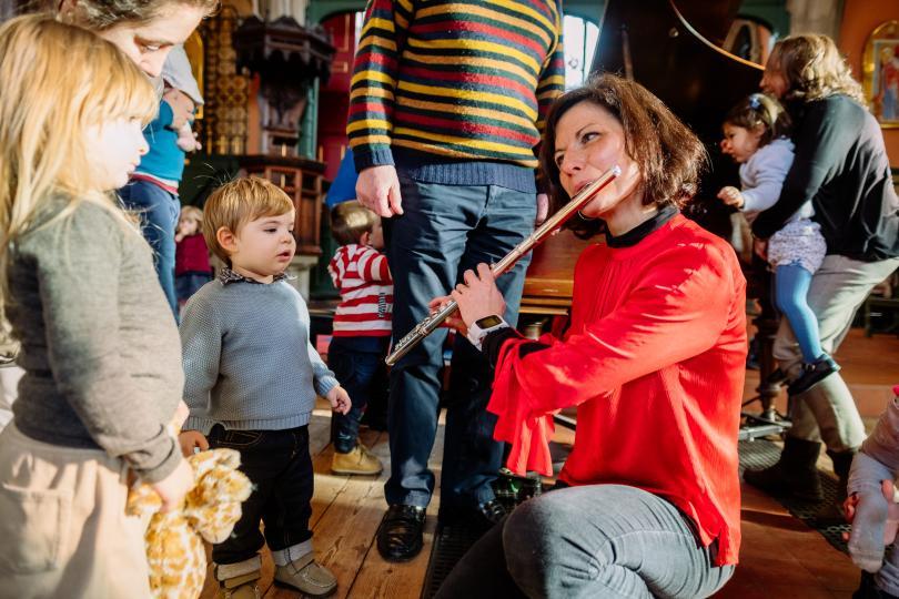 A flautist playing to a child and their parents at a Bach to Baby concert