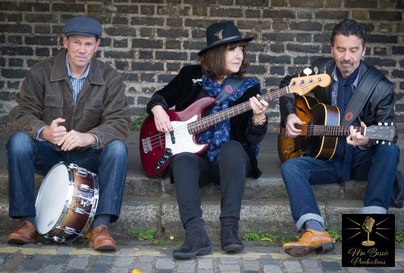 The Fran McGillivray Band sitting with instruments against a brick wall
