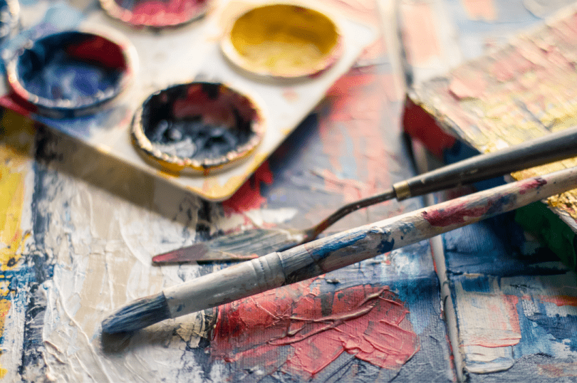 Watercolours and a paintbrush on a table