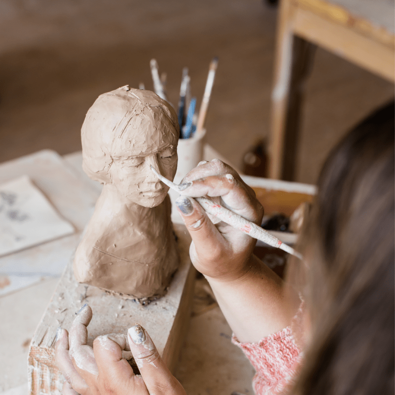 Hands sculpting a clay statue