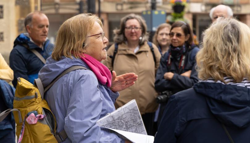 Woman in a lilac raincoat leading a walking tour