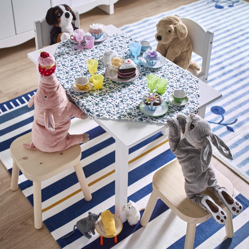 Stuffed animal toys sat around a dressed table having a tea party