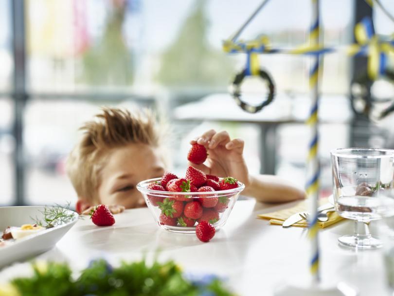 A swedish midsummer dinner table set with strawberries and a maypole decoration
