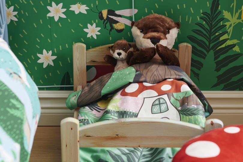 Baby and parent otter soft toys tucked in bed