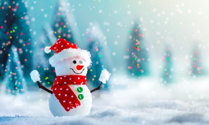 A happy snowman stands in a snowy scene wearing a bright red hat and scarf