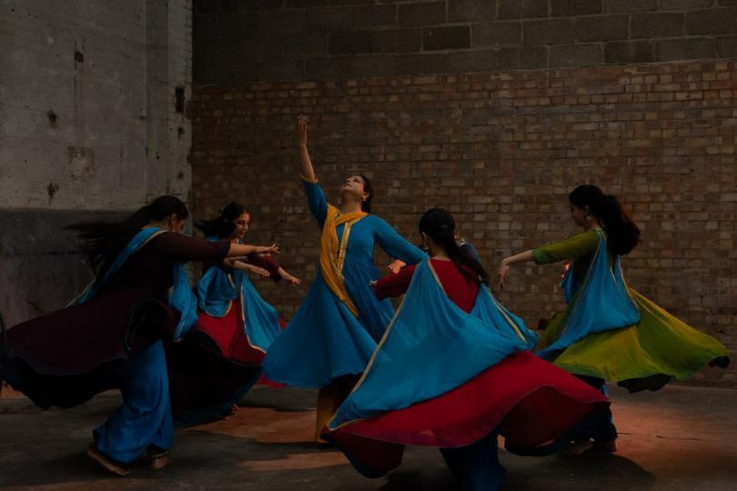 Five dancers in front of a brick wall