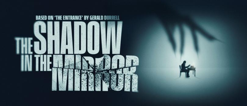 A large shadowy hand looms over a man seated at a desk