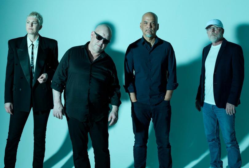 Members of he band Pixies against a bright turquois background