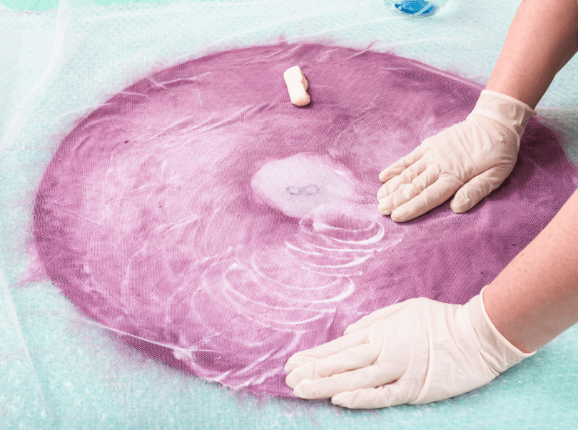 Hands working on pink wet felt