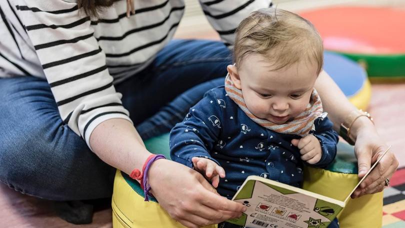 Adult reading a book to a baby