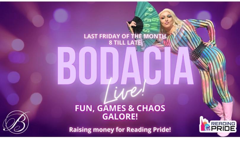 Drag queen in rainbow costume leaning on her own name