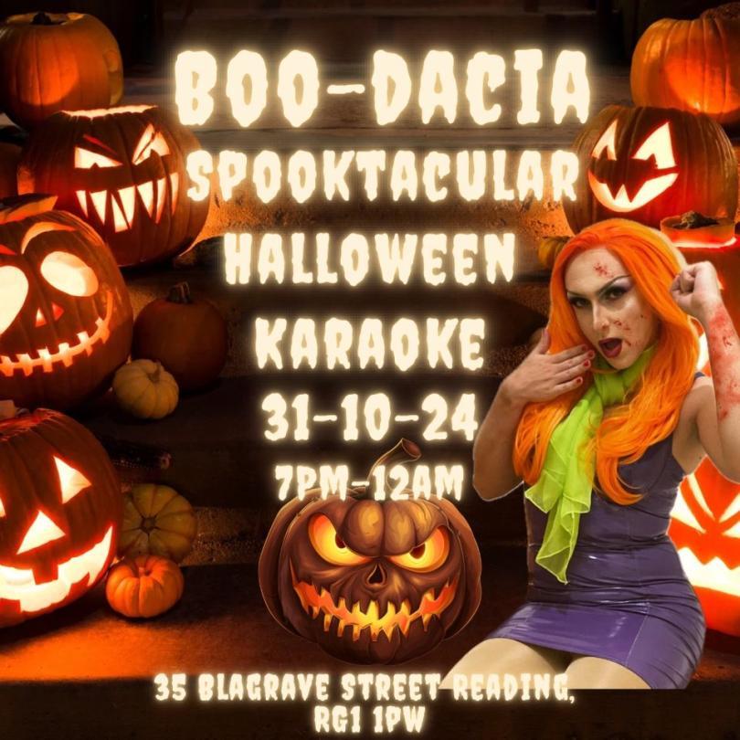Drag queen dressed as Daphne from scooby Doo in a bright orange wig and purple PVC dress against a background of jack o'lanterns