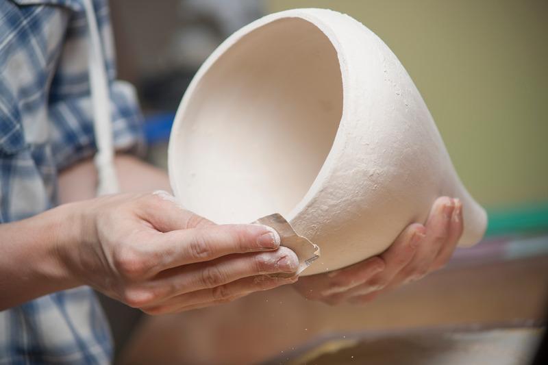 Hands shaping a ceramic pot