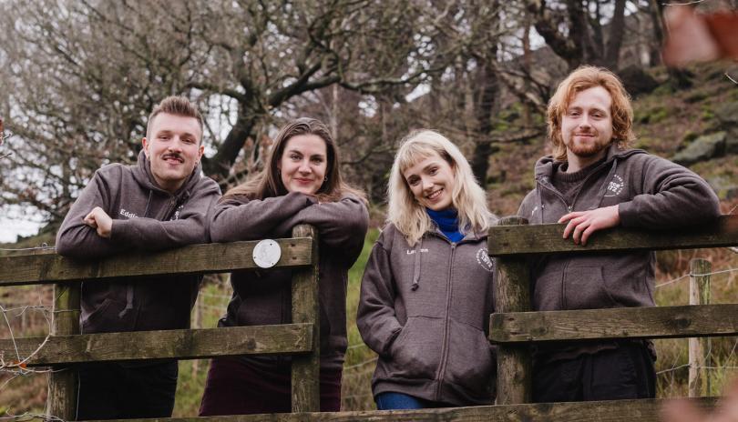 four actors stood behind a fence in the countryside