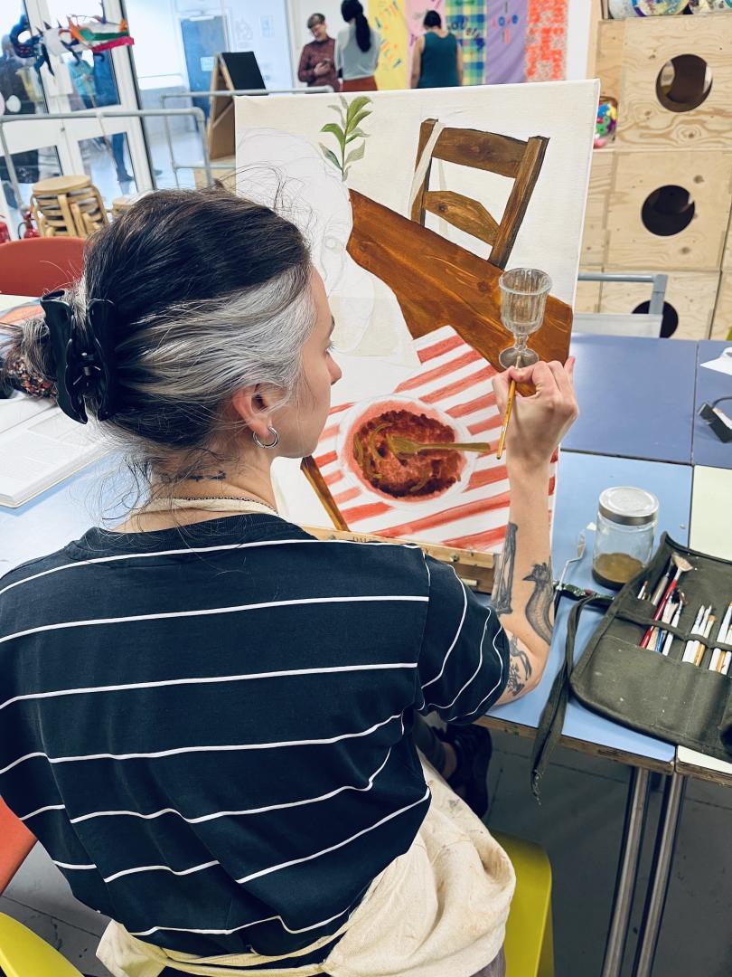 woman painting on an easel - seen of a dinner plate
