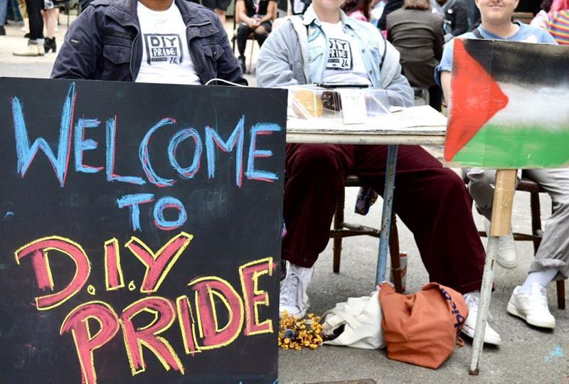 Volunteers sitting behind a desk, with a board in front saying "DIY pride"