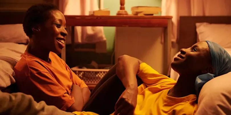 Screenshot from the film Dreamers with two black women smiling and sitting together