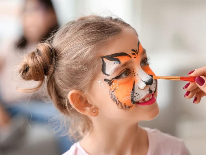 Girl with her face being painted as a tiger