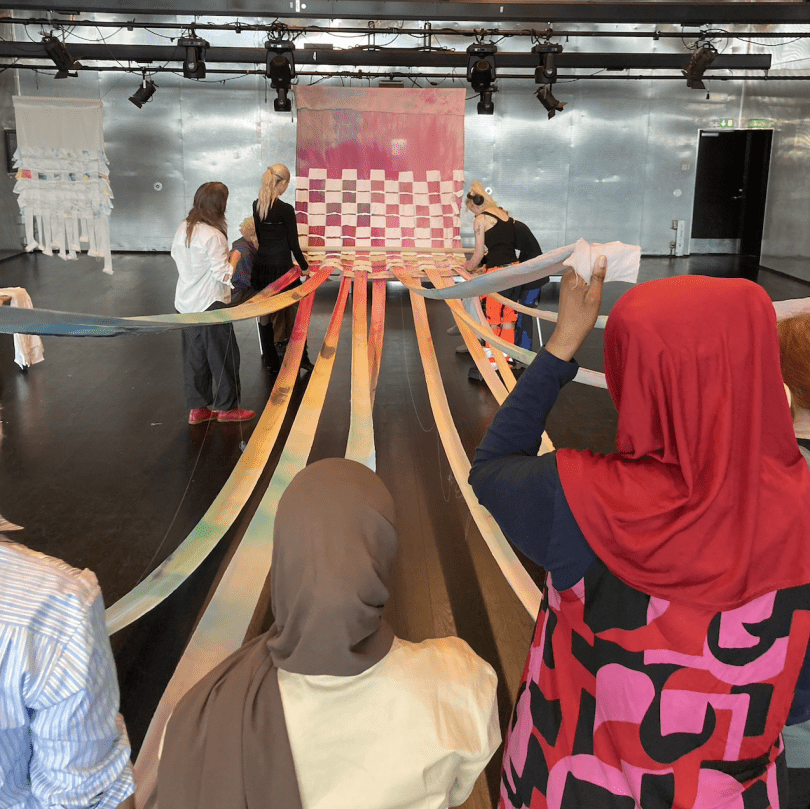 large woven material with people holding the fabric 