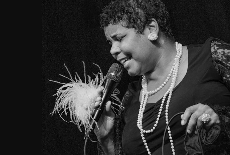 Singer Ma Bessie in vintage 1920s outfit singing into a microphone