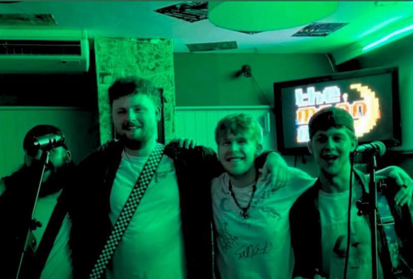 Green monochrome photo of four 20-something lads lined up in a pub