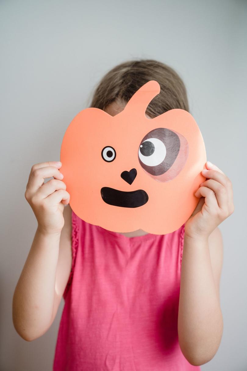 a young person with a pumpkin mask over their face