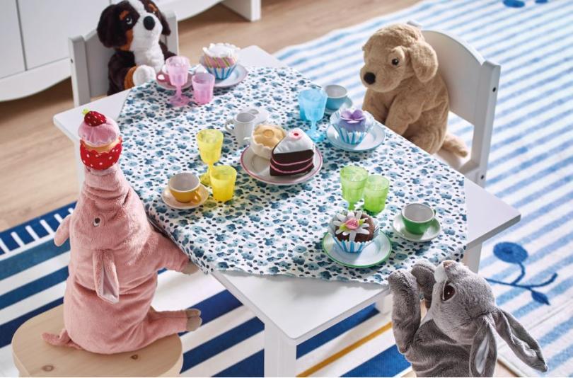 Stuffed toys sat around a childrens table having a tea party