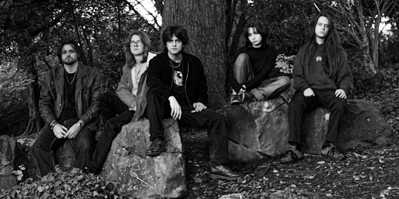 Black and white phot of a band sitting in a woodland