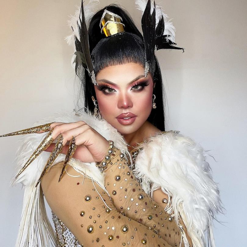 Drag queen Sum Ting Wong in an elaborate gold outfit with feathers and talon-like nails