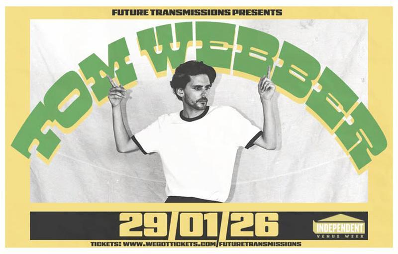 Tom Webber posing in a white t-shirt and black trousers