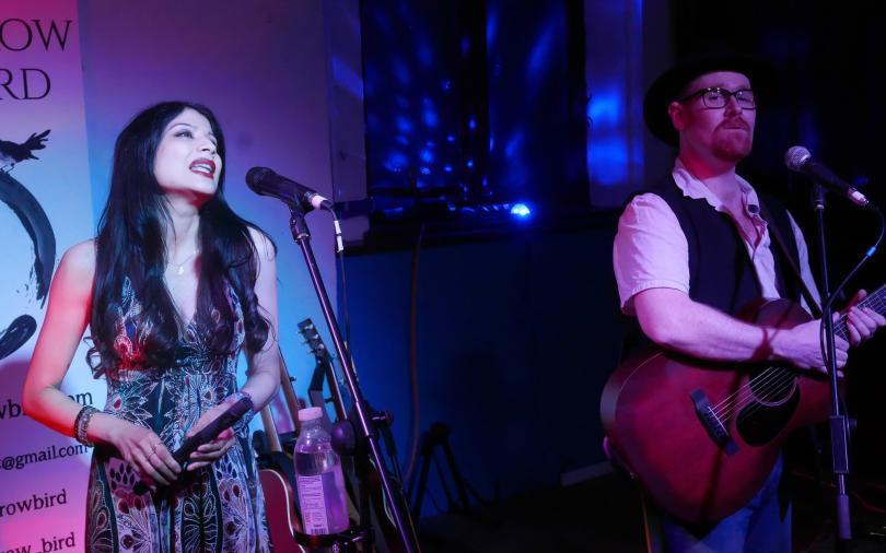 Tomorrow Bird on stage - a woman with long dark hair singing, and a man with glasses and a ginger beard playing guitar