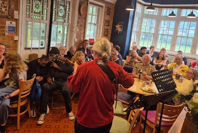 The back of a performer facing the audience at Tut's Open Mic night