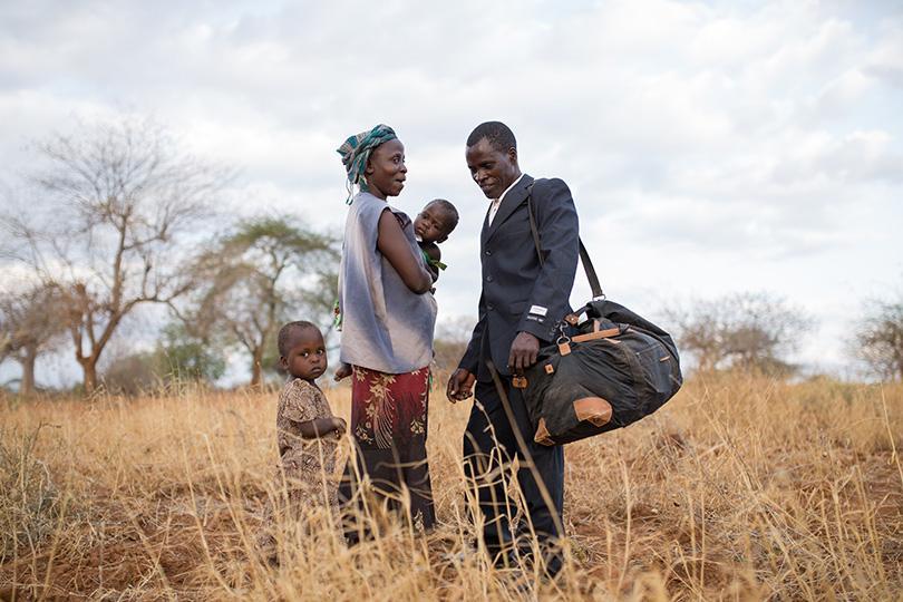 Still from the film "Thank You For The Rain" featuring an African family standing in the yellow grass of their homeland
